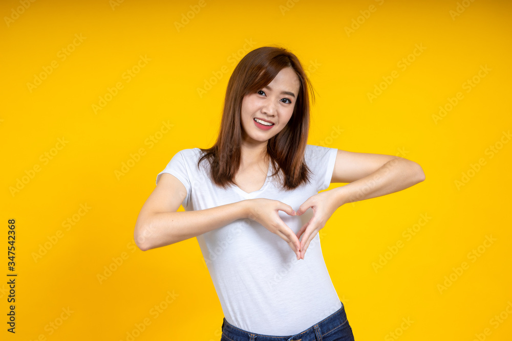 年轻优雅的亚洲女性微笑着，双手在黄色背景上做手势