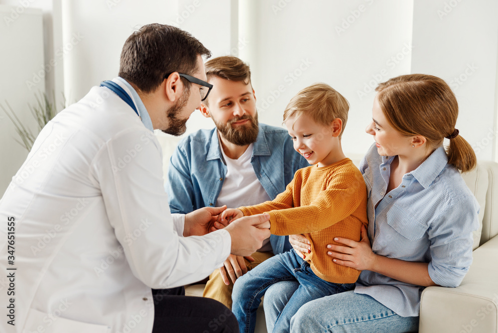 友好的医生牵着孩子的手，与男孩和父母交谈。