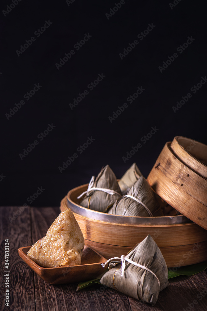 粽子-木桌上蒸笼里的中国粽子，黑色复古背景，代表龙