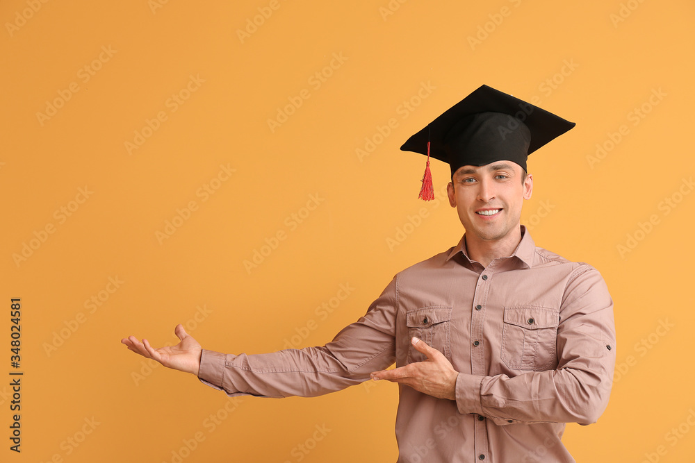 戴毕业帽的年轻人在彩色背景上展示了一些东西
