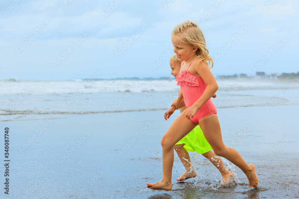 快乐的一家人在海滨度假胜地玩得很开心。小兄弟姐妹——有趣的男婴，年轻的女孩和spl一起跑步
