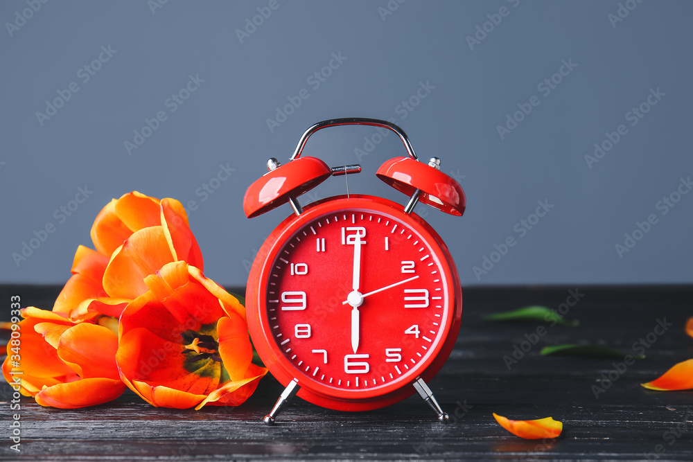 Alarm clock and flowers on table. Spring time
