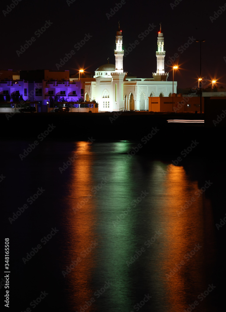 Night scene in the resort town. Featuring the lighthouse tower with lights reflection.