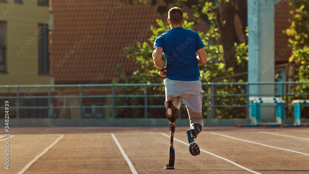 戴着假肢跑步刀片的运动型残疾人正在阳光下的户外体育场训练