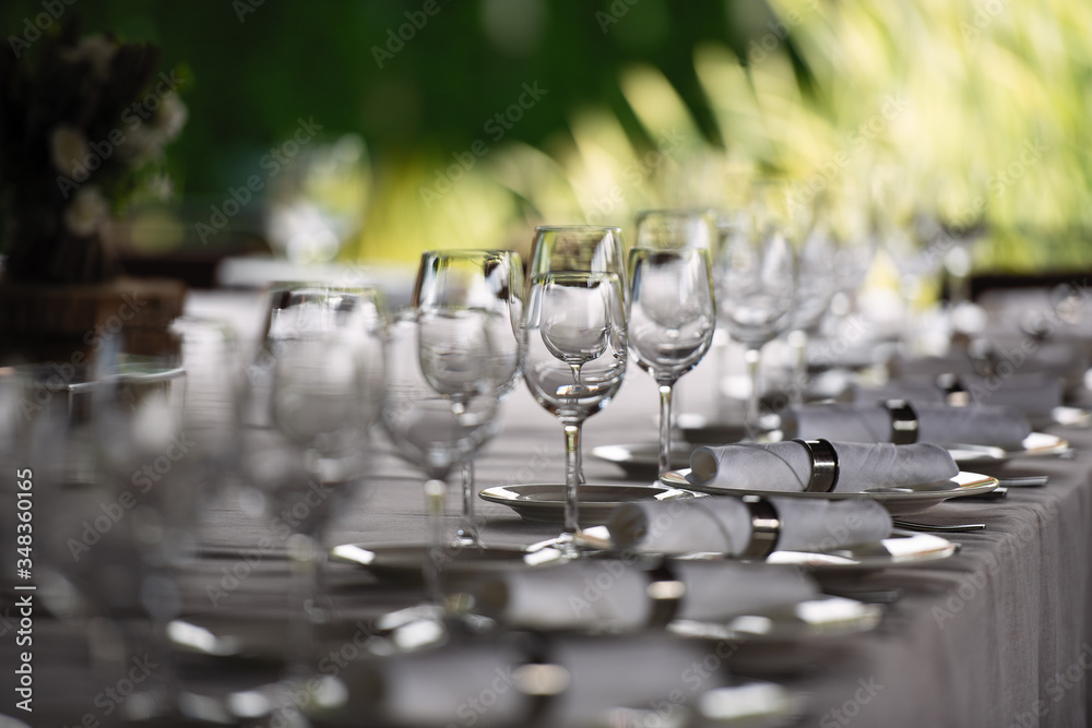 眼镜排成一排放在桌子上，公园户外餐厅的桌子，闪闪发光的盘子