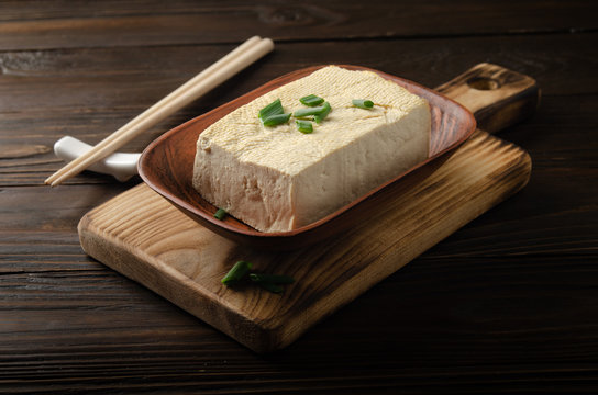 厨房餐桌上装在陶碗里的大豆豆腐蔬菜豆腐，旁边有韭菜和筷子