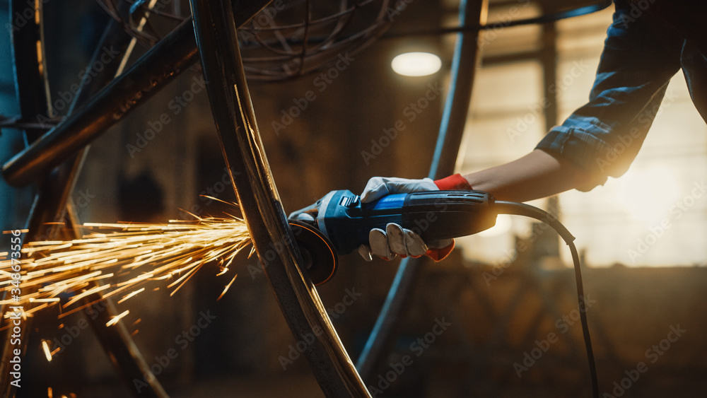 Close Up of Hands of a Metal Fabricator Wearing Safety Gloves and Grinding a Steel Tube Sculpture wi