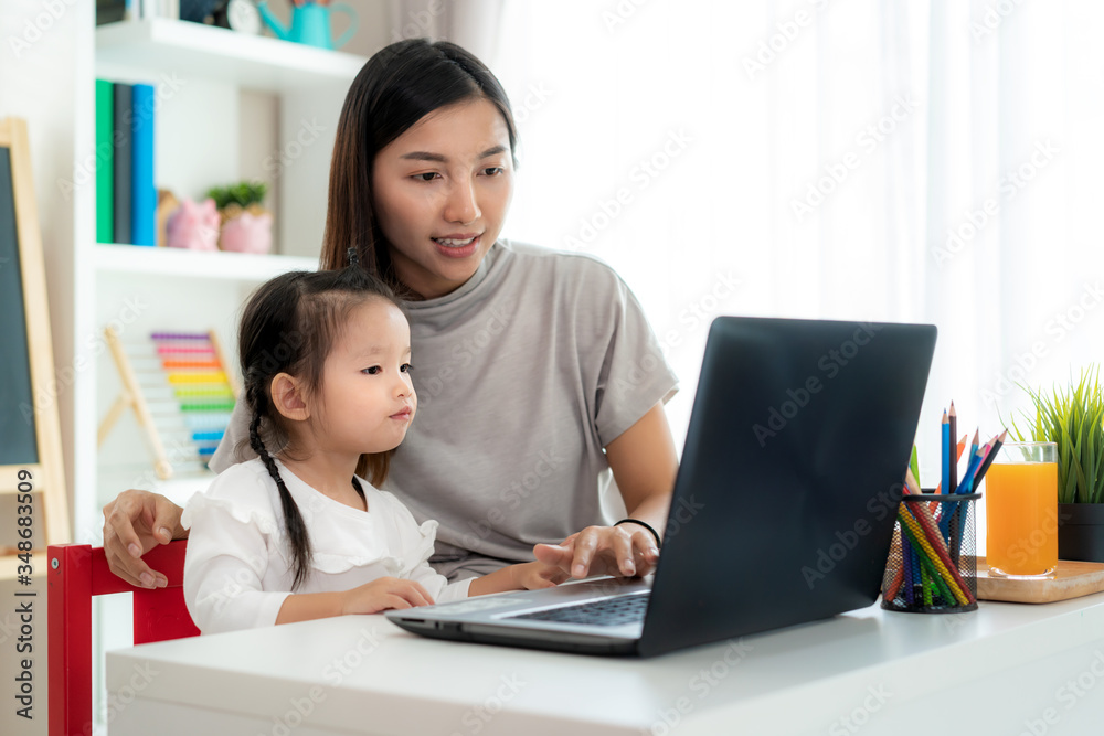 Asian kindergarten school girl  with mother video conference e-learning with teacher on laptop in li