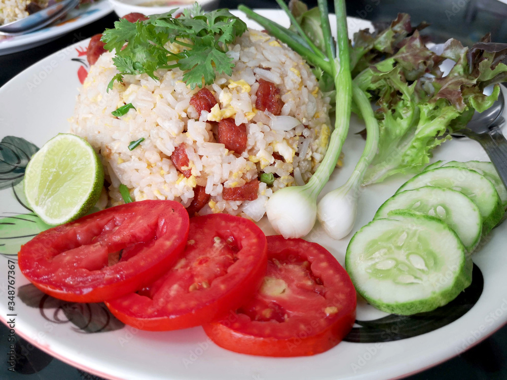 Chinese sausage fried rice with fresh tomatoes, spring onions, lime, cucumbers and lettuce as a side