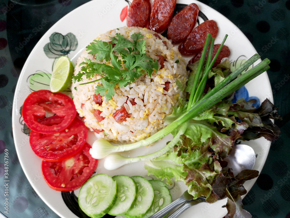 Chinese sausage fried rice with fresh tomatoes, spring onions, lime, cucumbers and lettuce as a side