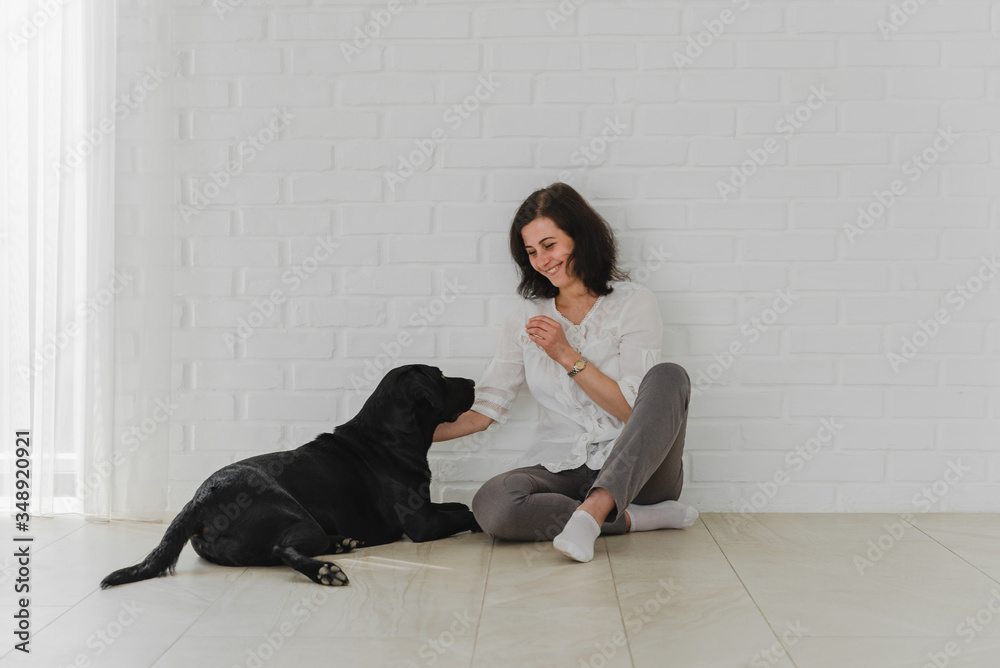 Cute young woman kisses and hugs her black labrador. Love between owner and dog. Isolated over white