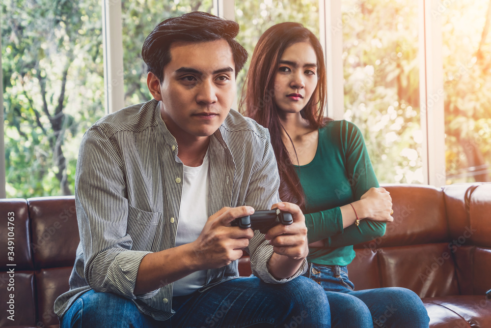 一对年轻的亚洲夫妇沉迷于电脑游戏。家庭问题概念。