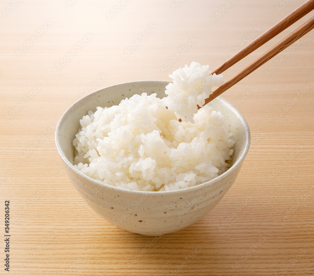 Scooping rice with chopsticks against a wooden background