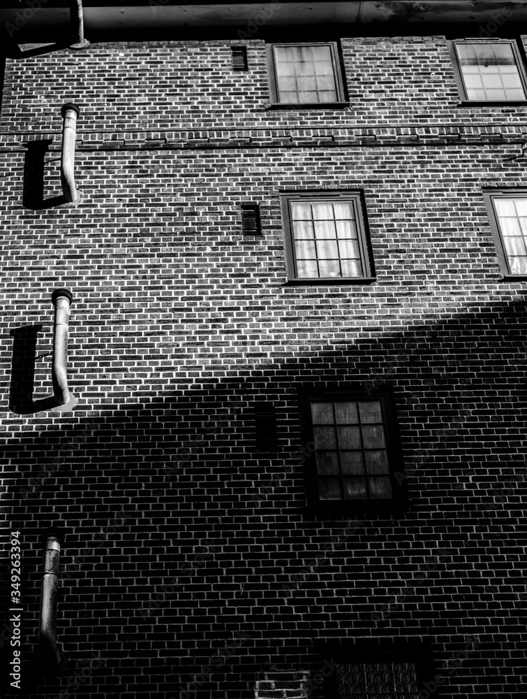 带窗户的旧砖墙。伦敦砖砌公寓正面的黑白照片。你