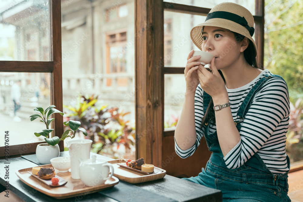 elegant asian korean lady tourist in denim overalls and straw hat sit on wooden floor in traditional