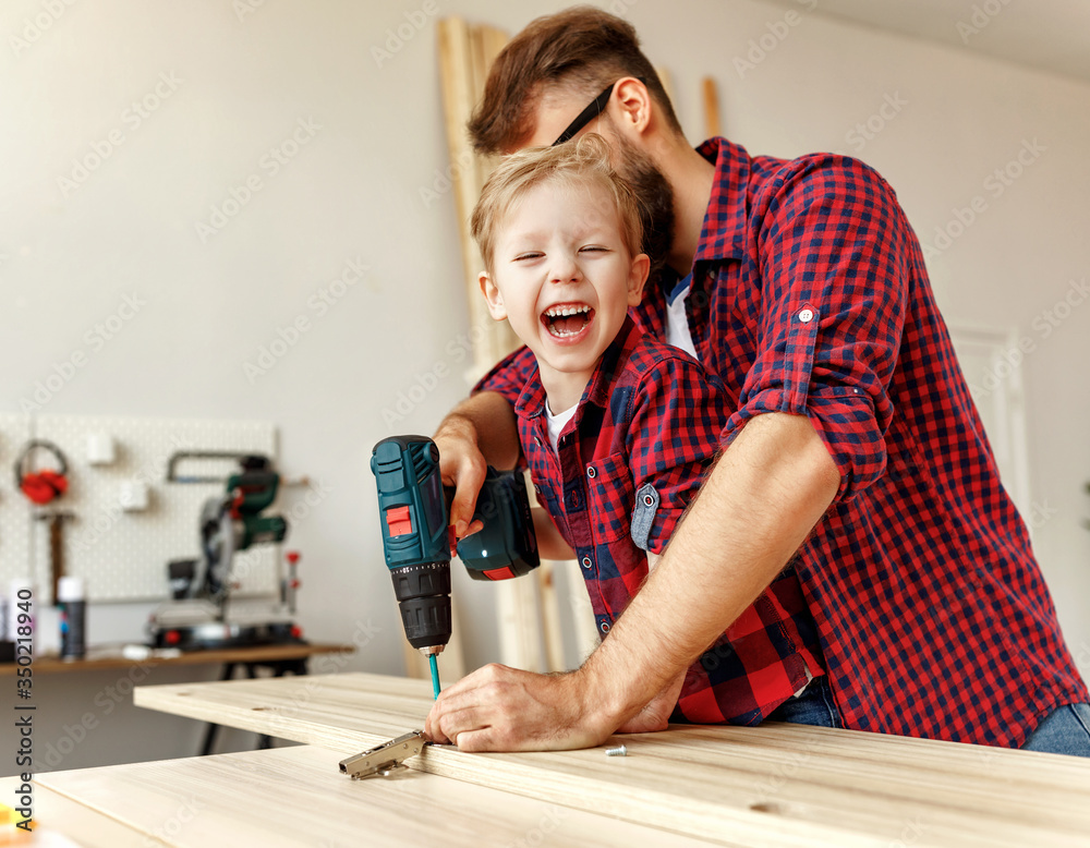 快乐的孩子在木工工作室帮助父亲。