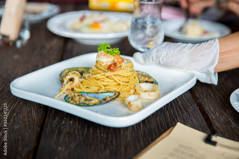 Seafood spaghetti in a white plate on an old wooden table