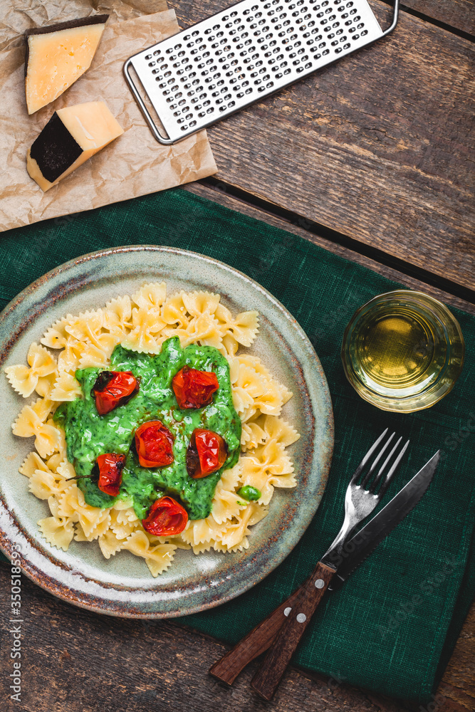 Pasta with tomato, parmesan cheese and basil on a wooden table. Farfalle and tomato on a plate on a 