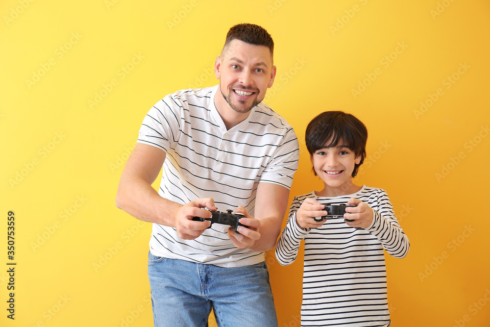 父亲和小儿子在彩色背景下玩电子游戏