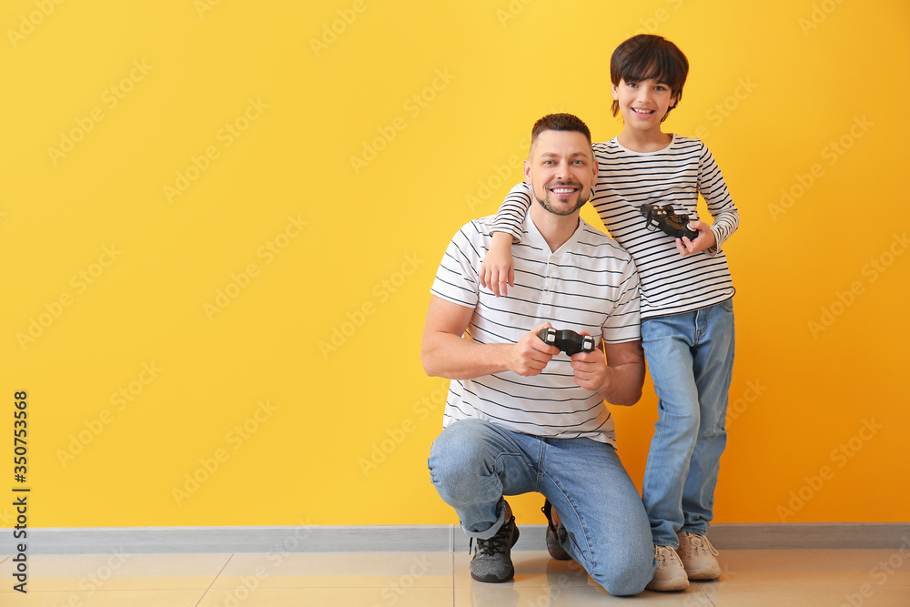 父亲和小儿子在彩色墙附近玩电子游戏