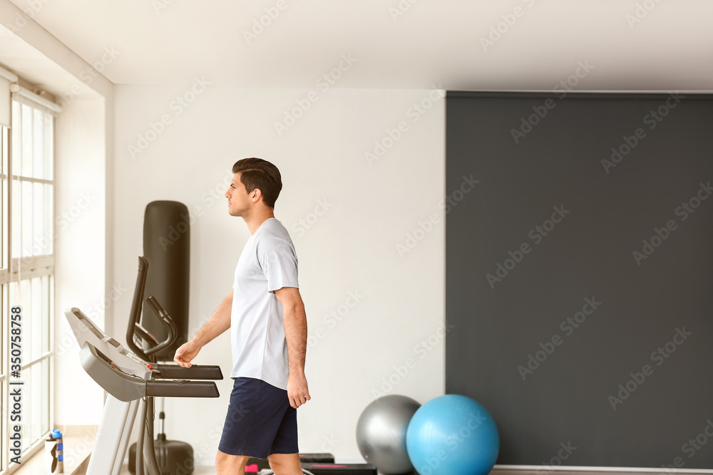 年轻人在健身房跑步机上训练