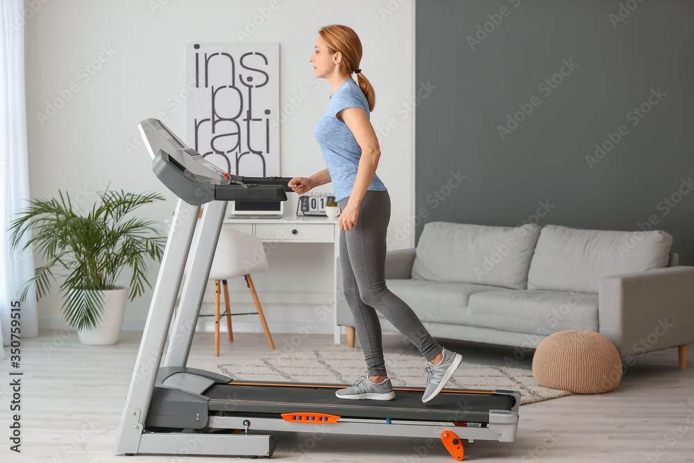 运动型女性在家跑步机上训练