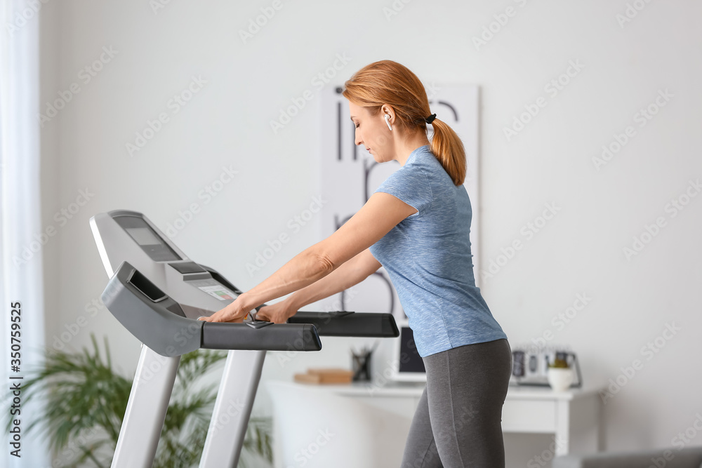 运动型女性在家跑步机上训练
