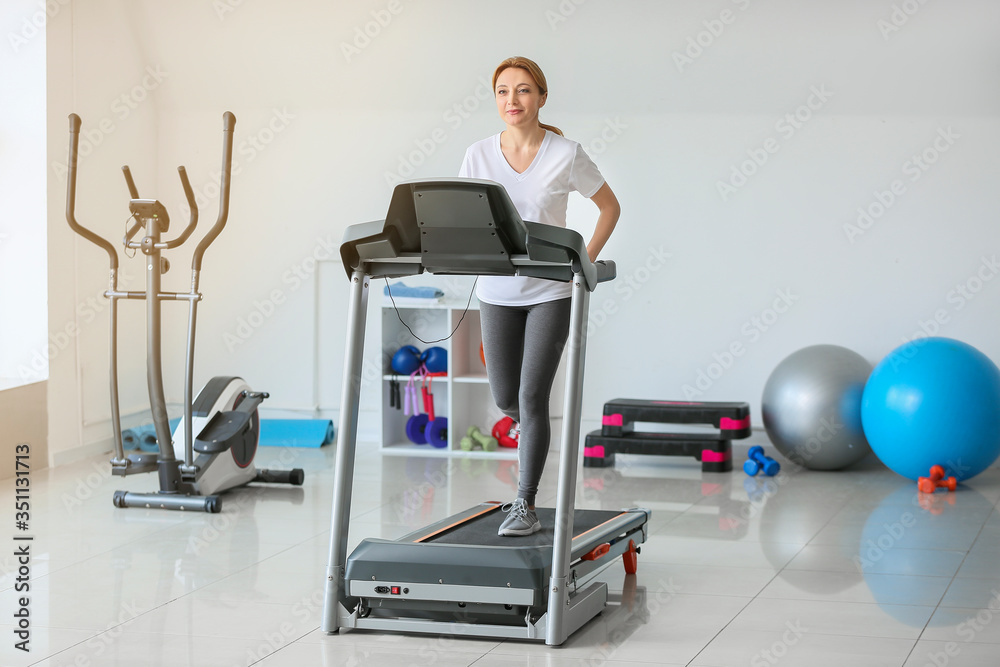 运动型女性在健身房跑步机上训练