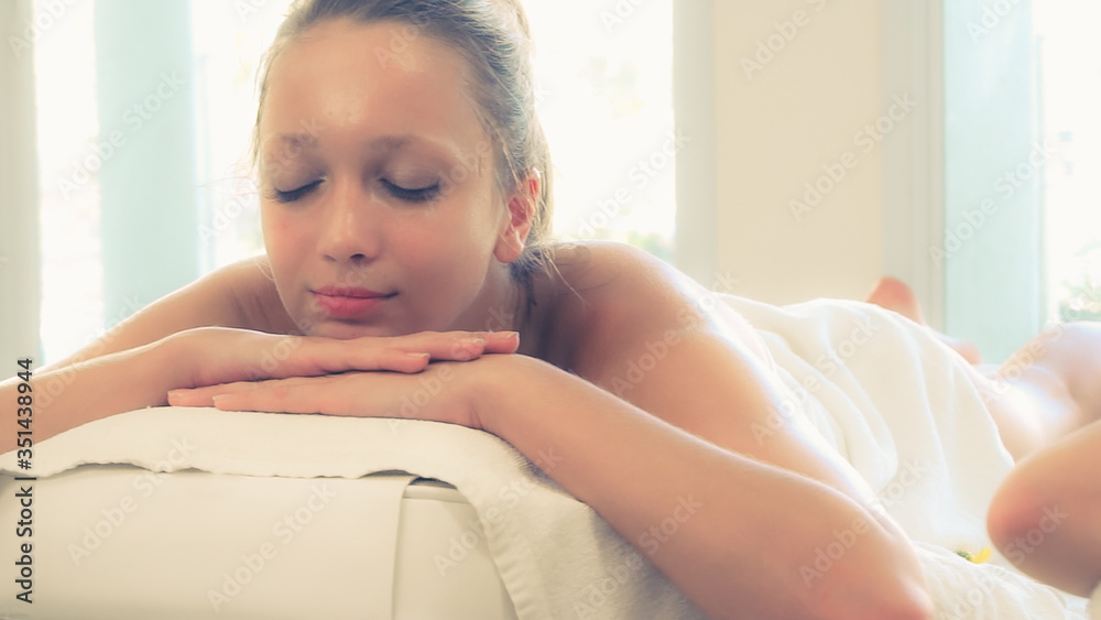 躺在水疗床上放松的年轻女子，准备在豪华水疗度假村进行面部护理和按摩。