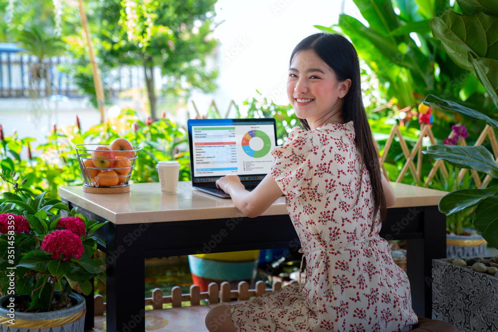亚洲女孩在花园里用笔记本电脑在家工作
