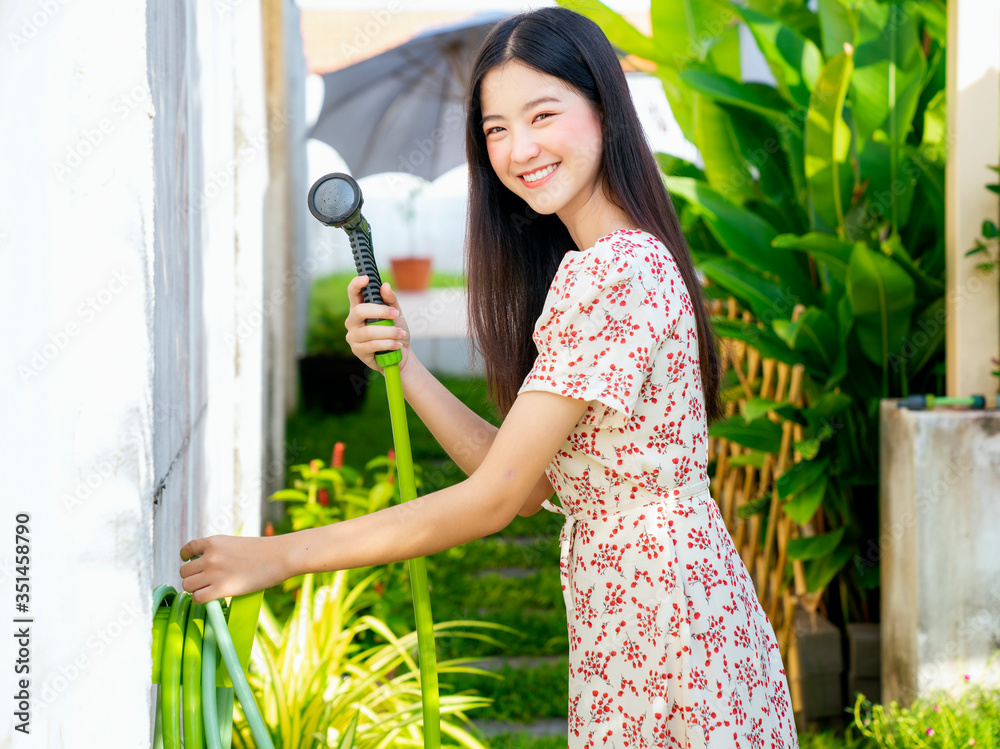 美丽的亚洲女人在阳台上浇灌绿色植物的肖像