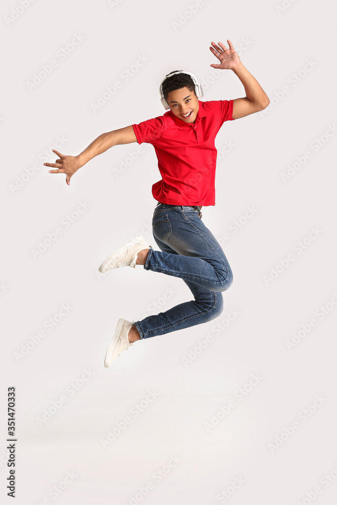 African-American teenager dancing and listening to music against light background