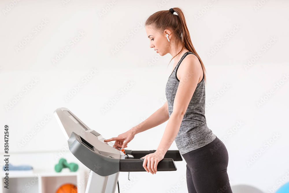 运动型年轻女性在健身房跑步机上训练