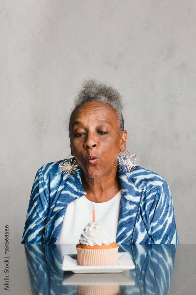 老年妇女在庆祝生日时在蛋糕上吹蜡烛