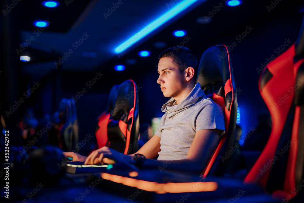 一个年轻人在网吧或游戏室玩电子游戏，坐在游戏椅上的肖像。