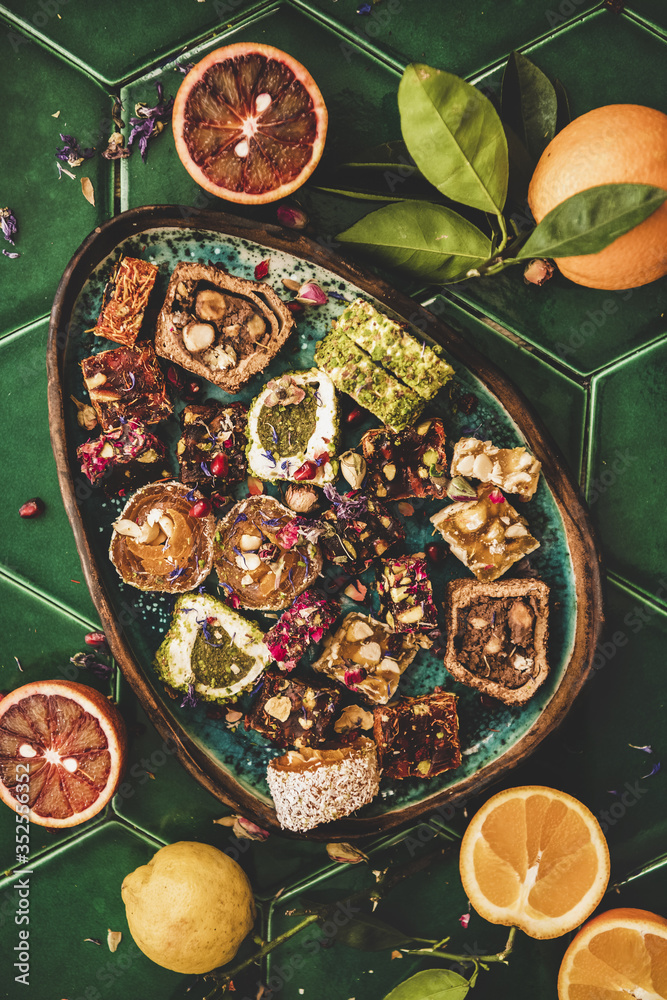 各种土耳其传统lokum甜乐在盘子里平躺，新鲜水果在绿色上