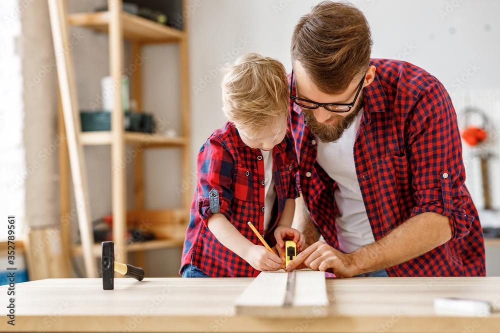 快乐的父子组装家具，用卷尺在桌子上测量木板。