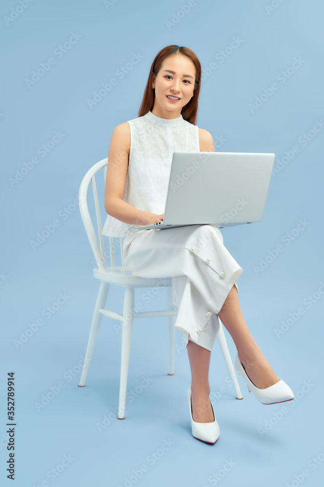 拿着笔记本电脑坐在椅子上的漂亮学生
