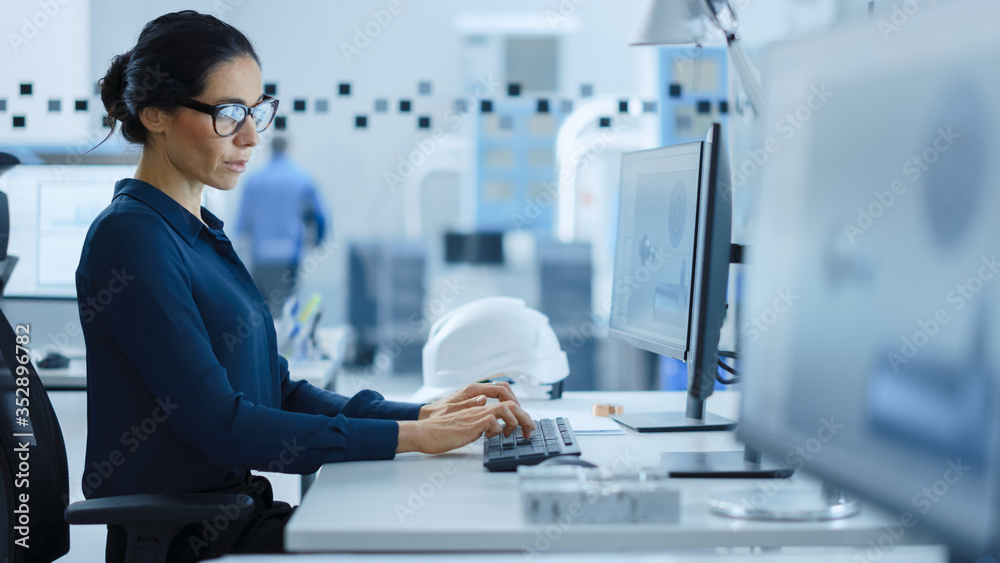 漂亮的女工程师在高科技工业工厂用个人电脑工作