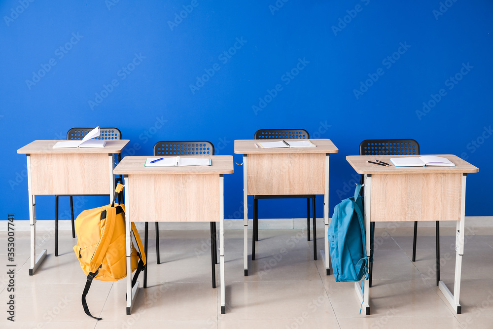 彩色墙附近的现代学校课桌