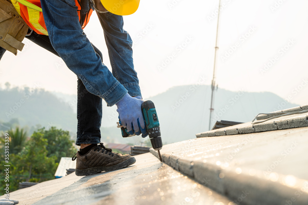 施工工程师穿着安全制服安装新屋顶，屋顶工使用空气或气动钉子