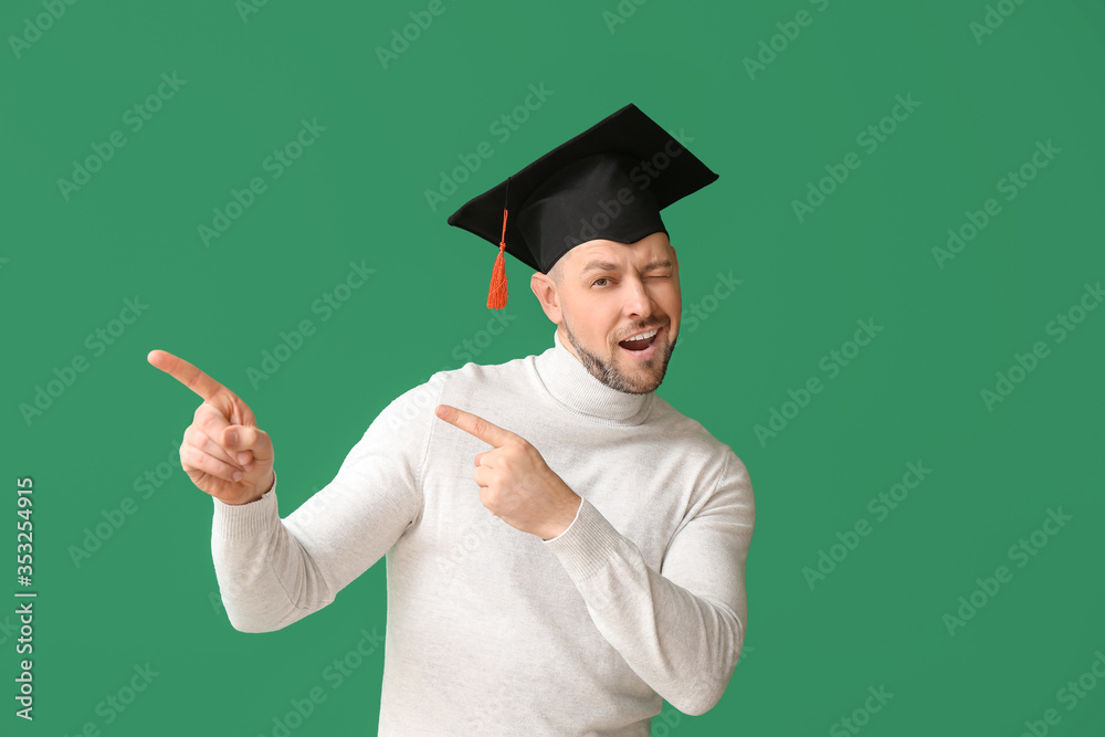 戴毕业帽的男子指着彩色背景上的东西
