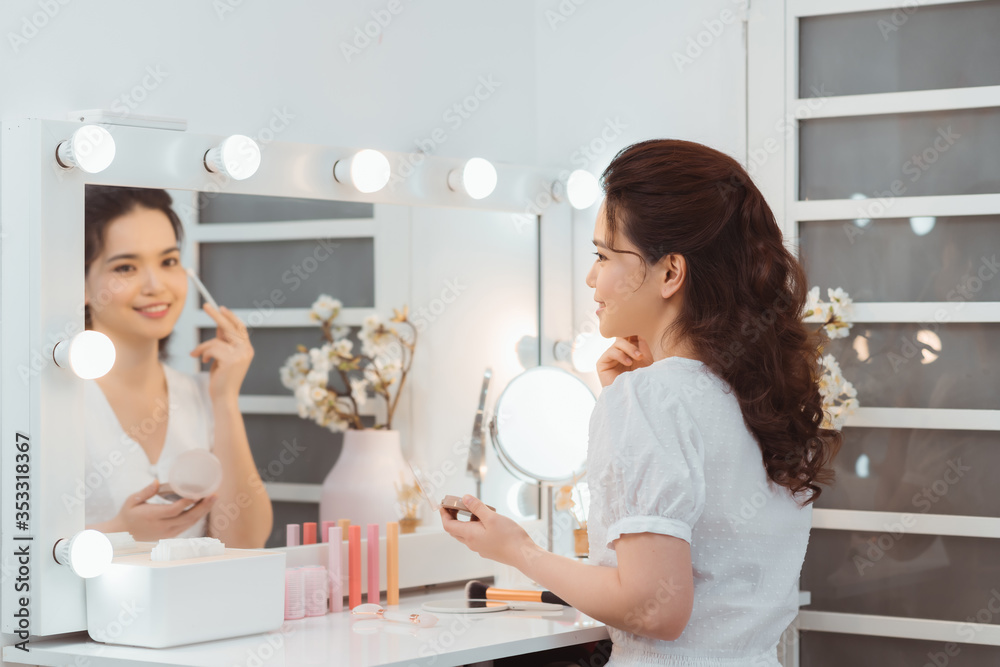 年轻时尚女性在镜子里用眼影刷化妆