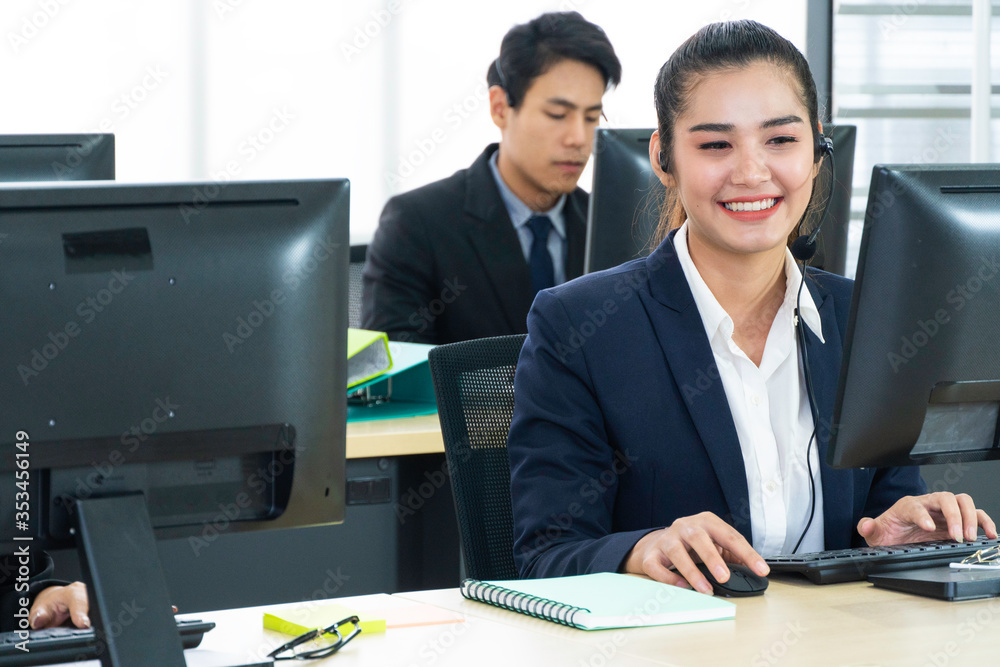 年轻的亚洲商务呼叫中心男男女女戴着耳机坐在办公桌上使用电脑wo