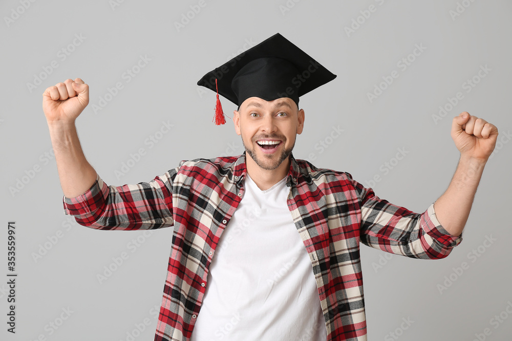 灰色背景戴毕业帽的快乐男人