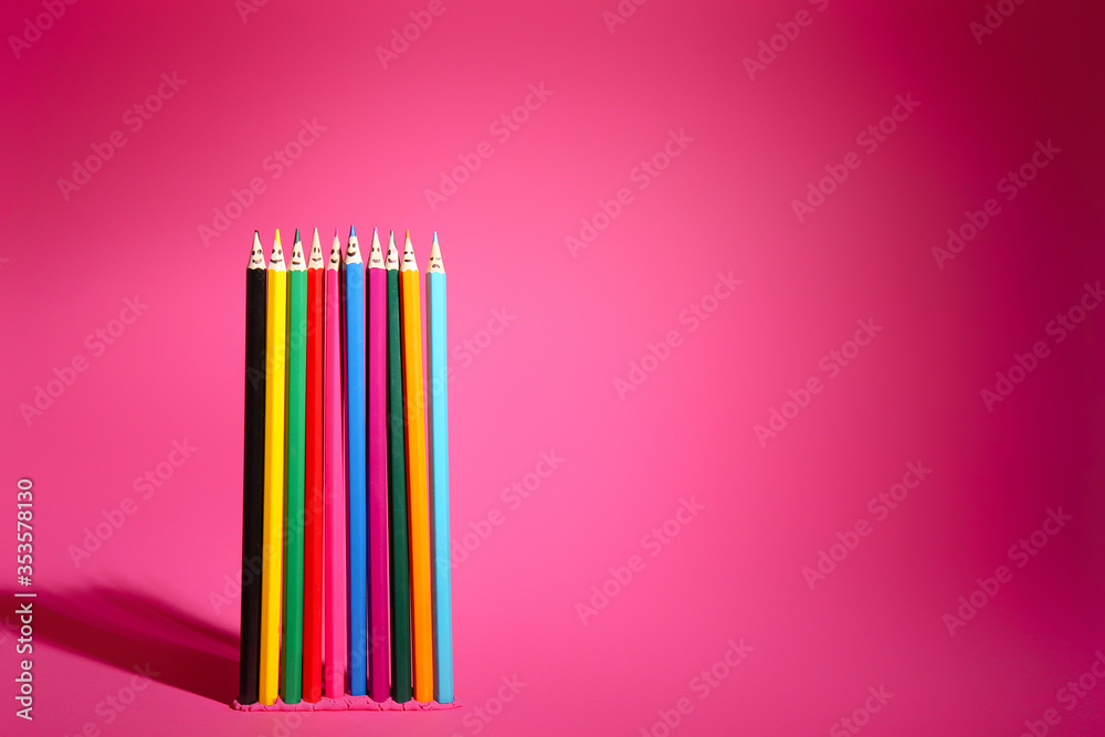 粉红色背景上画着脸的彩色铅笔。统一概念