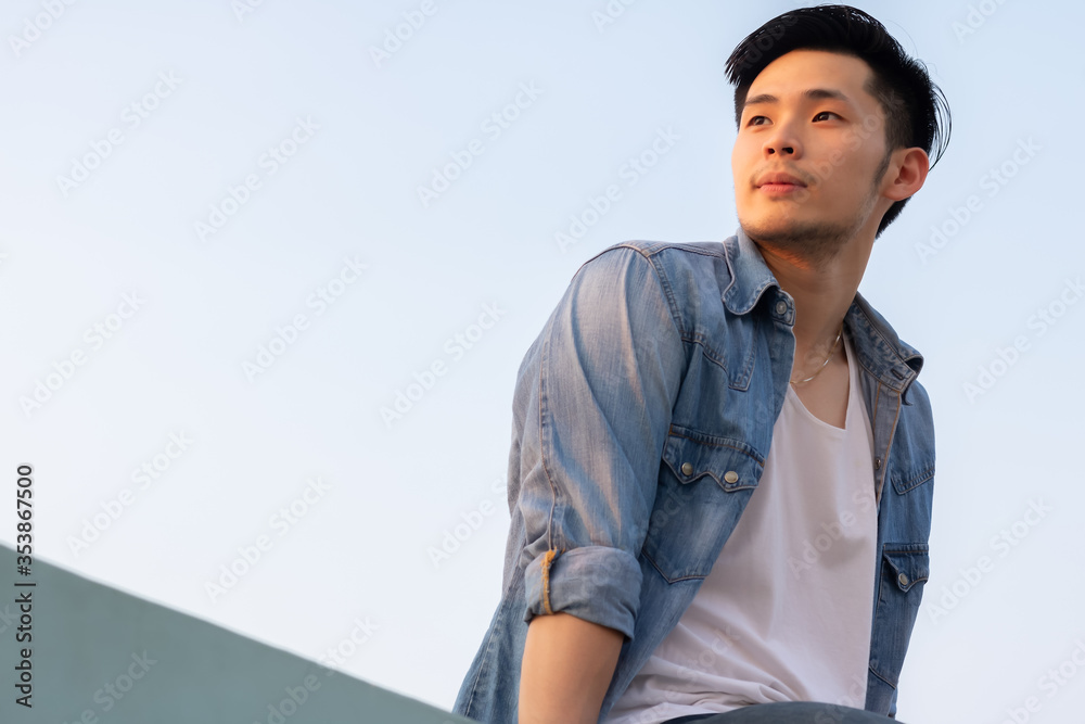 肖像英俊的亚洲年轻男子他看着美丽的日落，这让他很开心。有魅力的男人