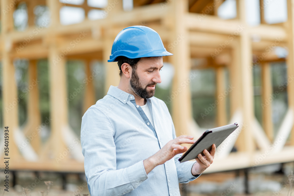 建筑师或建筑商在木屋结构附近用数字触摸板监督项目，