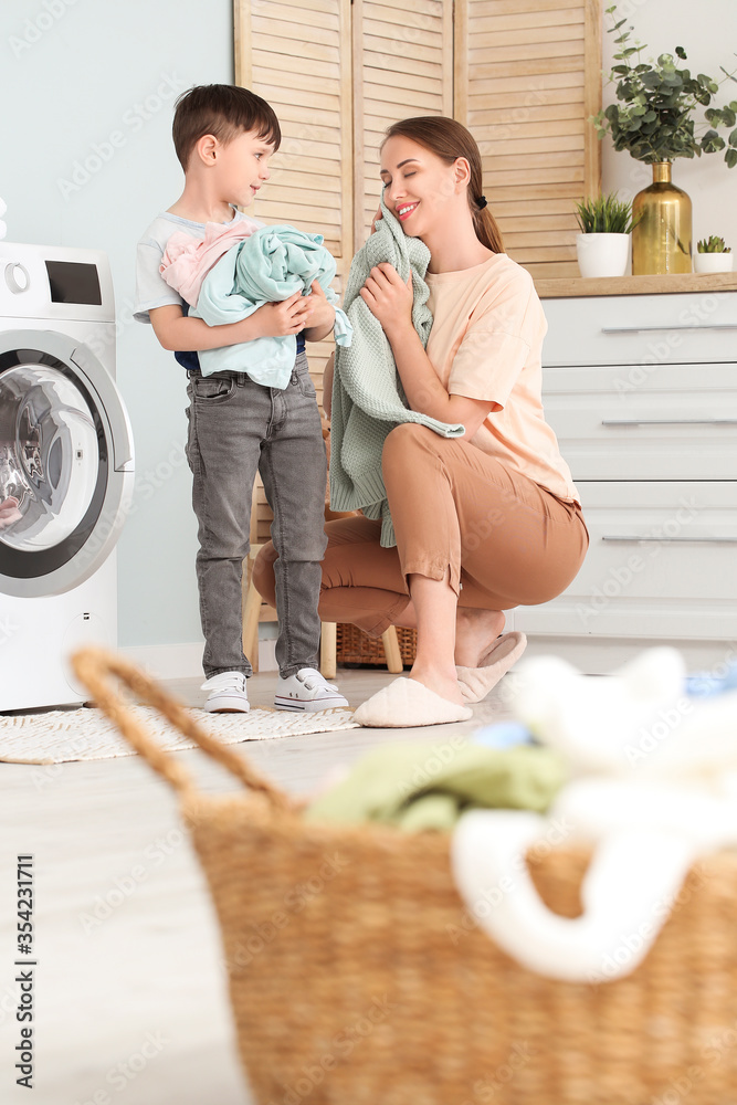 年轻女子带着她的小儿子在家洗衣服