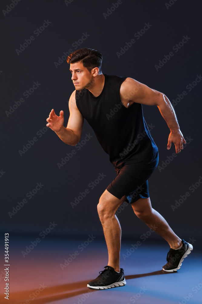 黑暗背景下的运动型年轻男性跑步者
